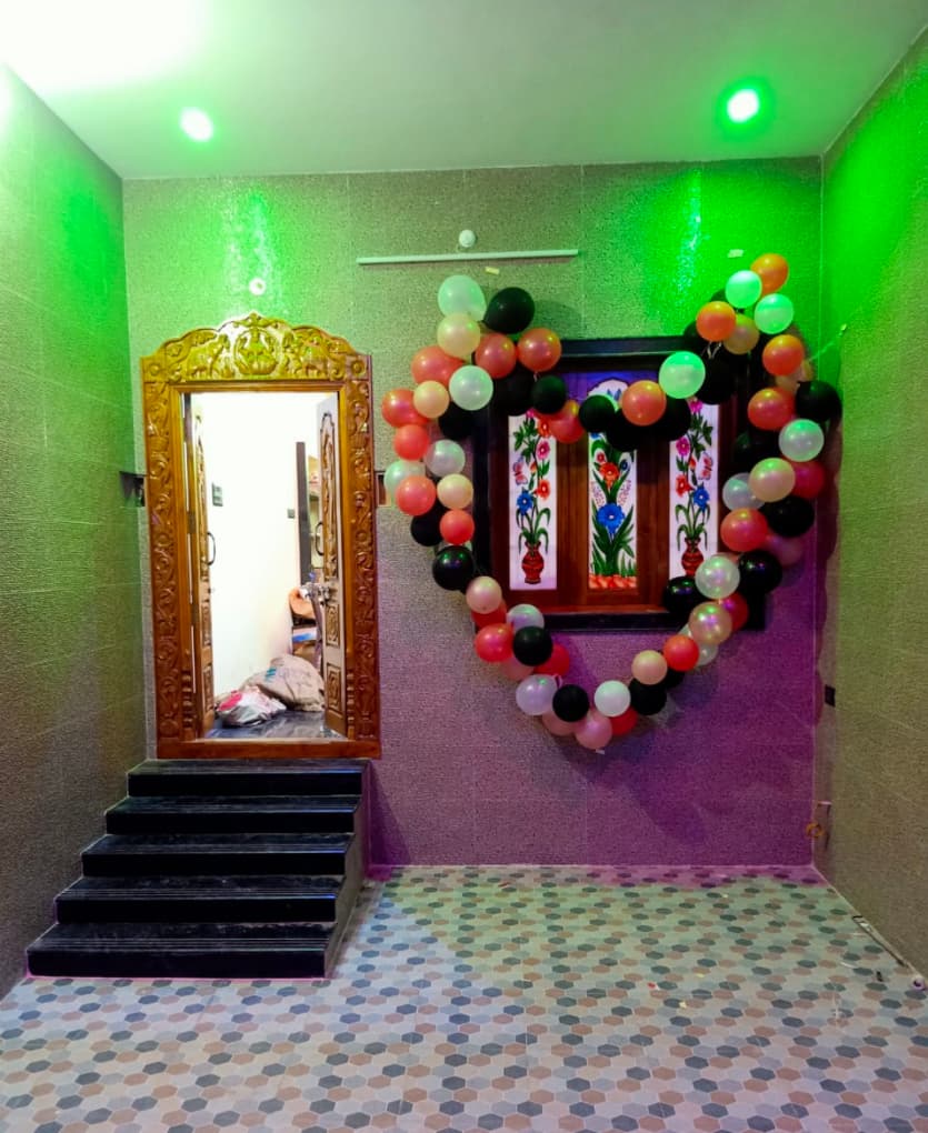 Heart shaped balloon arch around a window next to an ornate wooden doorway.